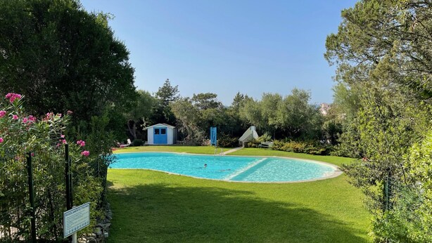 A swimming pool with a grassy area, a small shed, and a sign indicating pool regulations. - Casa Petralana by Wonderful Italy (Olbia)