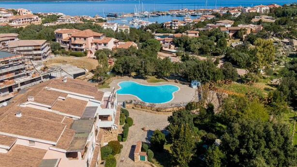 An aerial view of a coastal residential area with a large swimming pool surrounded by houses and greenery. - Sweet Mavy Incantevole Dimora by Wonderful Italy (Olbia)