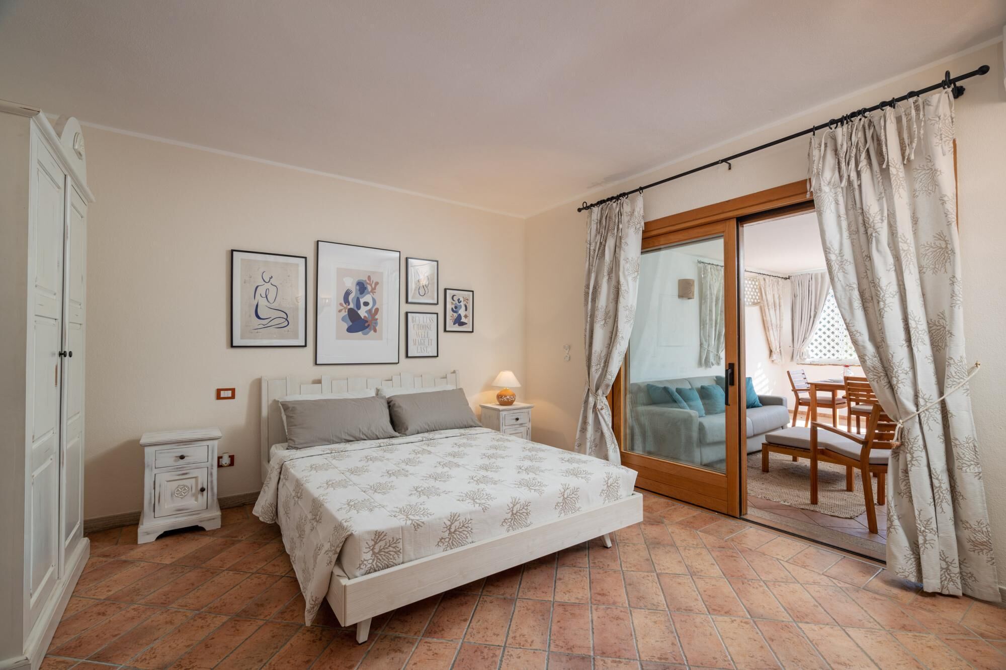Un dormitorio con cama, mesitas de noche y vistas al balcón a través de una puerta corrediza de vidrio.