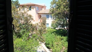 A view of a building with a tiled roof and a balcony, surrounded by greenery.