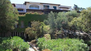 A multi-story building with a garden in front.
