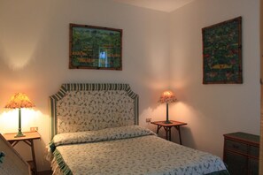 A bedroom with a bed, two wall-mounted lamps, and two framed pictures. - Casa Julia by Wonderful Italy (Olbia)