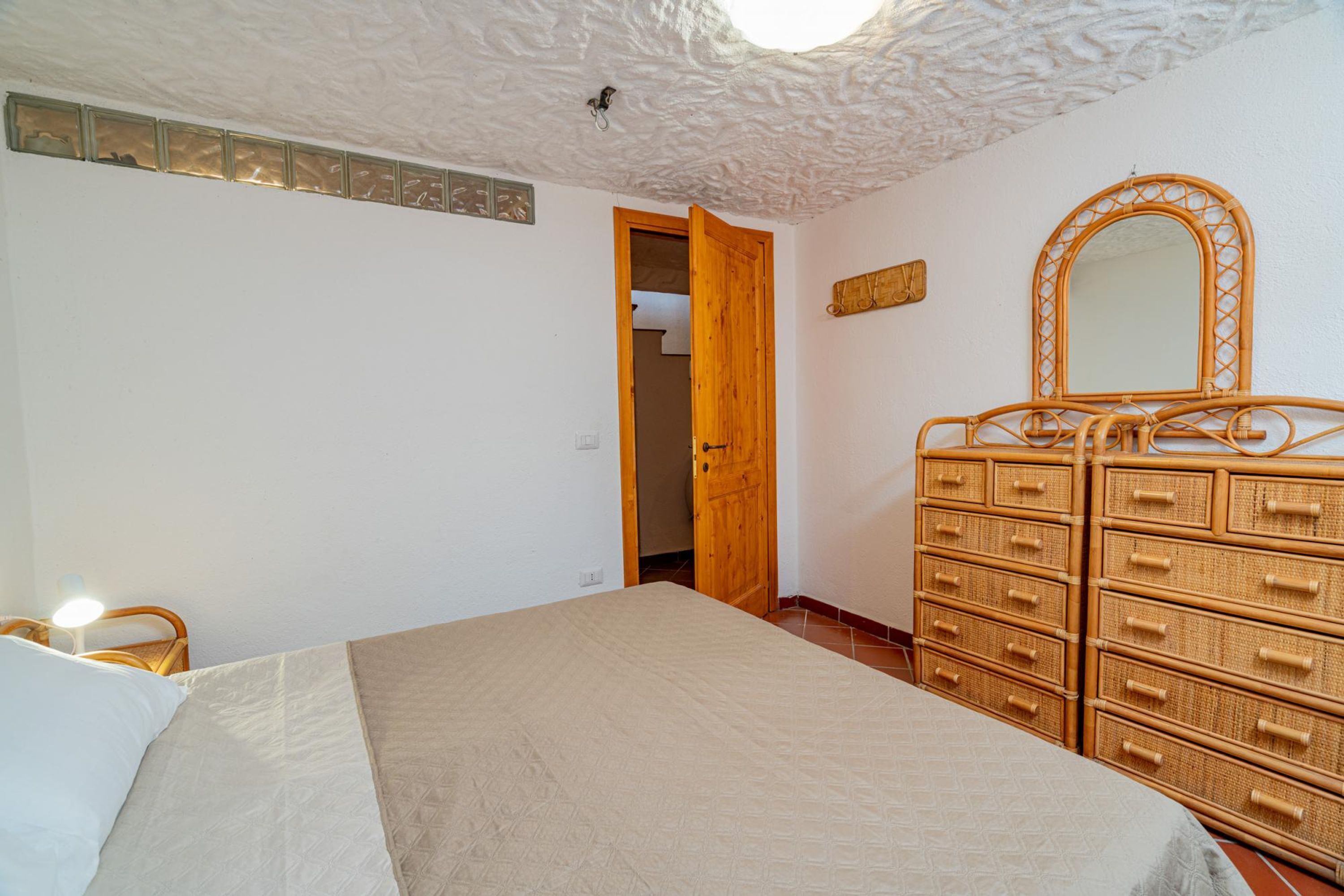 Une chambre à coucher avec un lit, une commode en bois et un miroir.