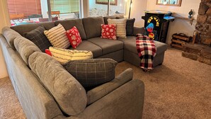 A cozy living room with a sectional sofa, a fireplace, and a large mirror.