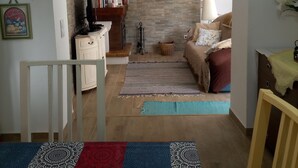 A living room with a sofa, a coffee table, a bookshelf, and a decorative rug. - O Mundo da Lua Casa Este (São Simão)
