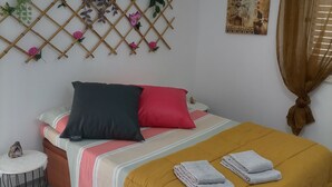 A neatly arranged bed with a yellow bedspread, multiple pillows, and a decorative wall hanging. - O Mundo da Lua Casa Este (São Simão)