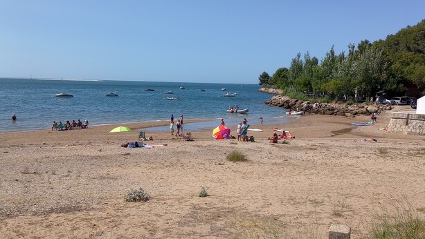 A beach with boats, people, and a stone wall. - O Mundo da Lua Casa Este (São Simão)