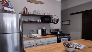A modern kitchen with a stainless steel refrigerator, wooden countertop, and a stove. There are cabinets below the countertop and a coffee maker on the counter. - 2feather inn #2 (Natchez)