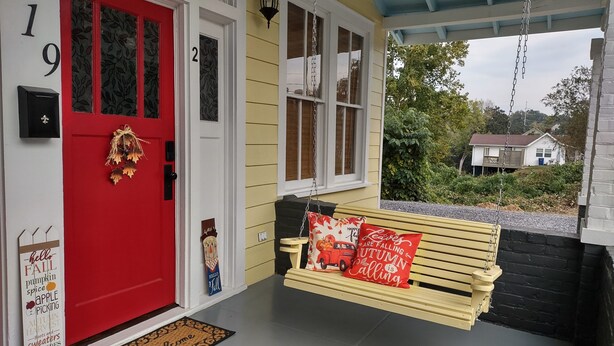 A porch with a red door, a bench with a red cushion, and a welcome mat. - 2feather inn #2 (Natchez)
