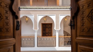 An interior courtyard with ornate wooden doors, white arches, and decorative metal railings. - Riad Nelia (Marrakech)