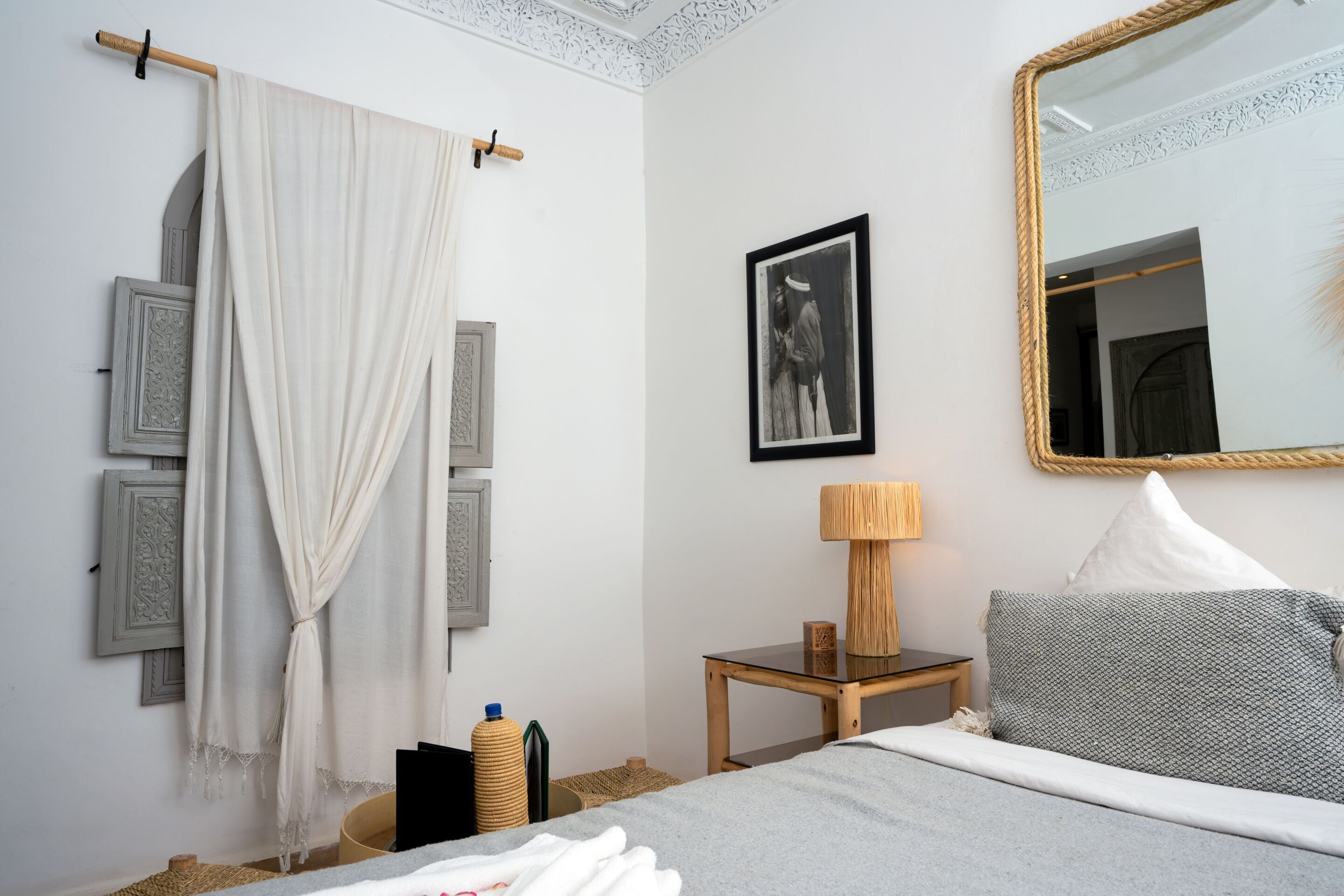 Una camera da letto con un letto, un comodino con una lampada, uno specchio e un quadro appeso al muro.