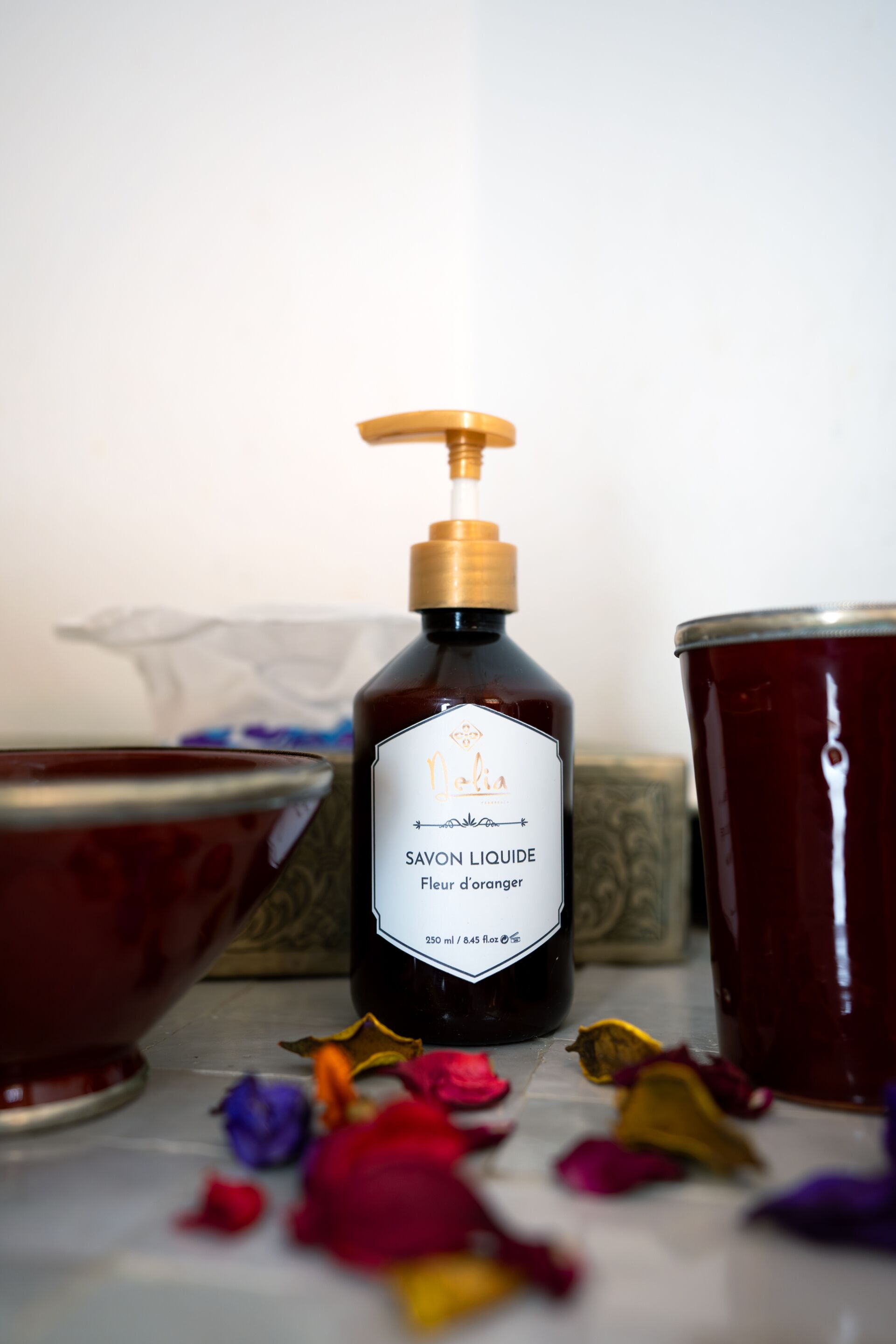 Una botella de Savon Liquide con dispensador de bomba, un cuenco y un frasco con una sustancia blanca.