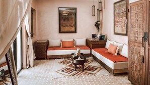 A cozy room with a sofa set, a decorative rug, and a hanging light fixture. - Riad Nelia (Marrakech)