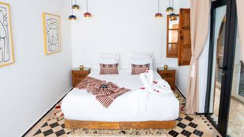 Un dormitorio ordenado con una cama grande, mesitas de noche e iluminación colgante.