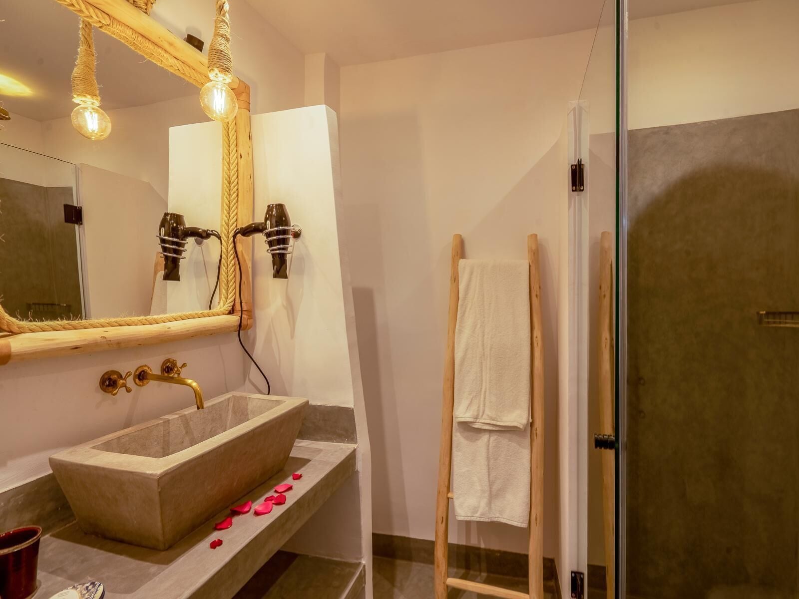 A bathroom with a large mirror, a vessel sink, a towel rack, and a shower area.