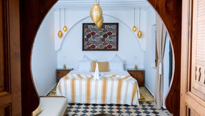 A bedroom with a checkered floor, a bed with striped bedding, a decorative hanging light, and a framed artwork on the wall. - Riad Nelia (Marrakech)