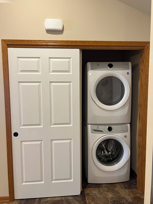 A laundry room with a white door and two stacked washing machines.