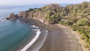Un paysage côtier comprenant une plage, une côte rocheuse et une végétation luxuriante.