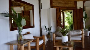 Un intérieur en bois comprenant un canapé, des fauteuils, une table et des plantes en pot.