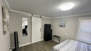 Ein Schlafzimmer mit Bett, Schminktisch, Fernseher, Spiegel und Deckenleuchte.