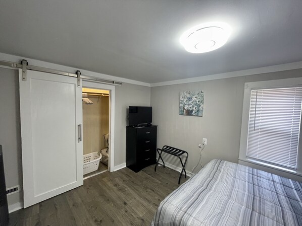 A bedroom with a bed, a closet, a dresser, a television, and a window with blinds. - Full home short walk to Memorial stadium, Hawks field, Railyard & Pinnacle arena (Lincoln)
