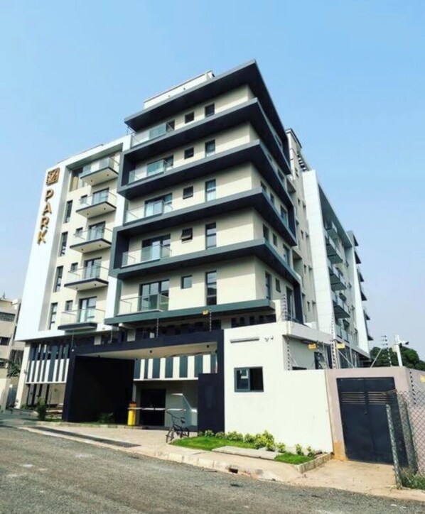 A multi-story building with a modern design, featuring balconies and a parking garage.