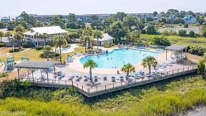 Una grande piscina esterna circondata da lettini e palme, con vista su edifici residenziali sullo sfondo.