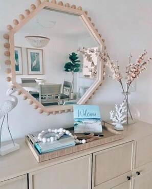 Une coiffeuse agrémentée d’un miroir décoratif, un panneau d’accueil et un plateau contenant des objets décoratifs.