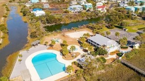 Vista aerea di una zona residenziale con una grande piscina, diverse case e un fiume.