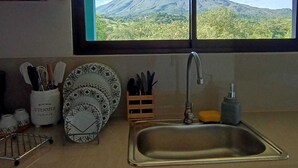 A kitchen with a window view of a volcano. - Villa Luna del Arenal (La Fortuna)