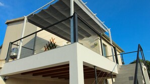 Un bâtiment moderne doté d’un balcon, d’un escalier et surplombant un ciel bleu dégagé.