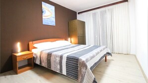 Un lit bien fait, avec une couverture à rayures, une lampe de chevet et une table de nuit.