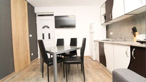 Une cuisine compacte avec un coin repas, un téléviseur fixé au-dessus du comptoir et une porte en bois.