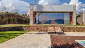 Un edificio moderno con ventanas amplias, una pared de piedra y una terraza de madera.