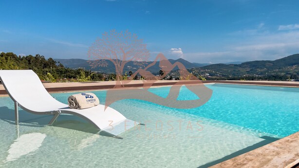Piscina cristalina con una silla de descanso blanca y una toalla, con vistas a montañas y vegetación.