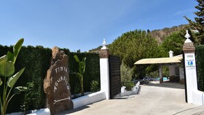 A gated entrance with a sign reading "Finca Guajaiola" and a covered parking area with a pool.