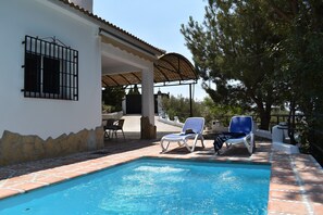 A swimming pool with two lounge chairs, a covered patio, and a stone wall. - Finca Aguaillo - a 20-minute walk from the village (Cómpeta)