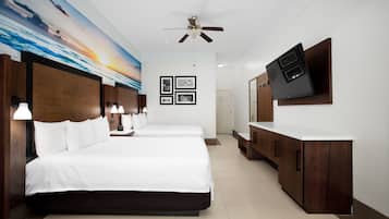 A hotel room with a large bed, a desk, a television, and a ceiling fan.