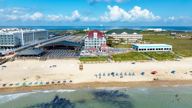 A beachside hotel with multiple buildings, a sandy beach, and a view of the ocean.