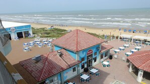 A beachside restaurant with outdoor seating and a pool.