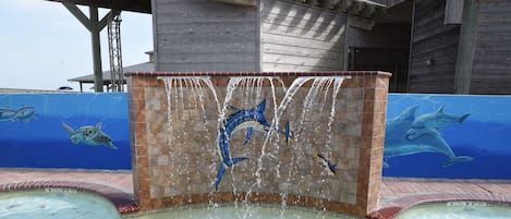 Una piscina con fuente de agua y murales de vida marina.