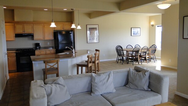 A modern kitchen with wooden cabinets, a black refrigerator, and a dining area with a table and chairs.