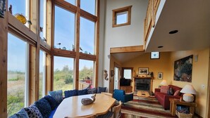 A cozy living room with a wooden dining table, blue patterned sofa, and a fireplace.