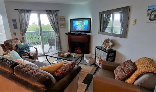 A living room with a sofa, armchairs, a coffee table, a fireplace, and a television displaying Earth.