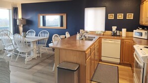 A compact kitchen with a dining area, wooden cabinets, a microwave, a toaster, and a sink. - Windsong # 6 Beautiful condo with partial ocean view (Ocean Shores)