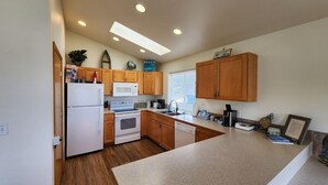 A modern kitchen with wooden cabinets, a white refrigerator, a microwave, an oven, and a dishwasher.