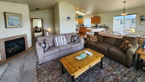 A spacious living room with a fireplace, a large gray sofa, a brown sofa, and a wooden coffee table.