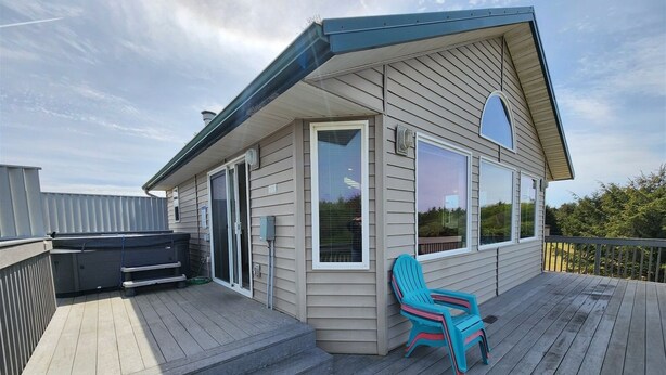 A deck with a blue chair, a grill, and a sliding glass door.