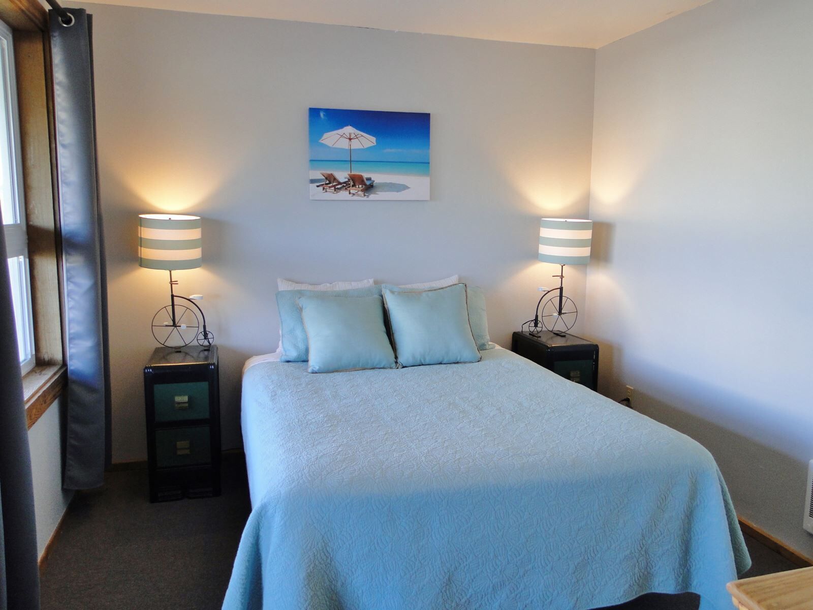 Een keurig opgemaakt slaapkamer met een bed, twee nachtkastjes en een wandlamp.