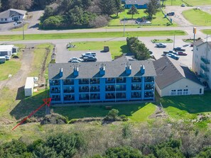 A multi-story building with a flat roof, surrounded by a parking lot and greenery.
